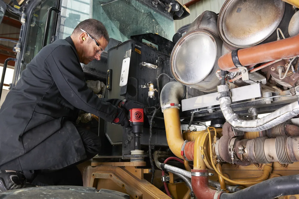 Technician using a Chicago Pneumatic impact wrench on a heavy diesel engine